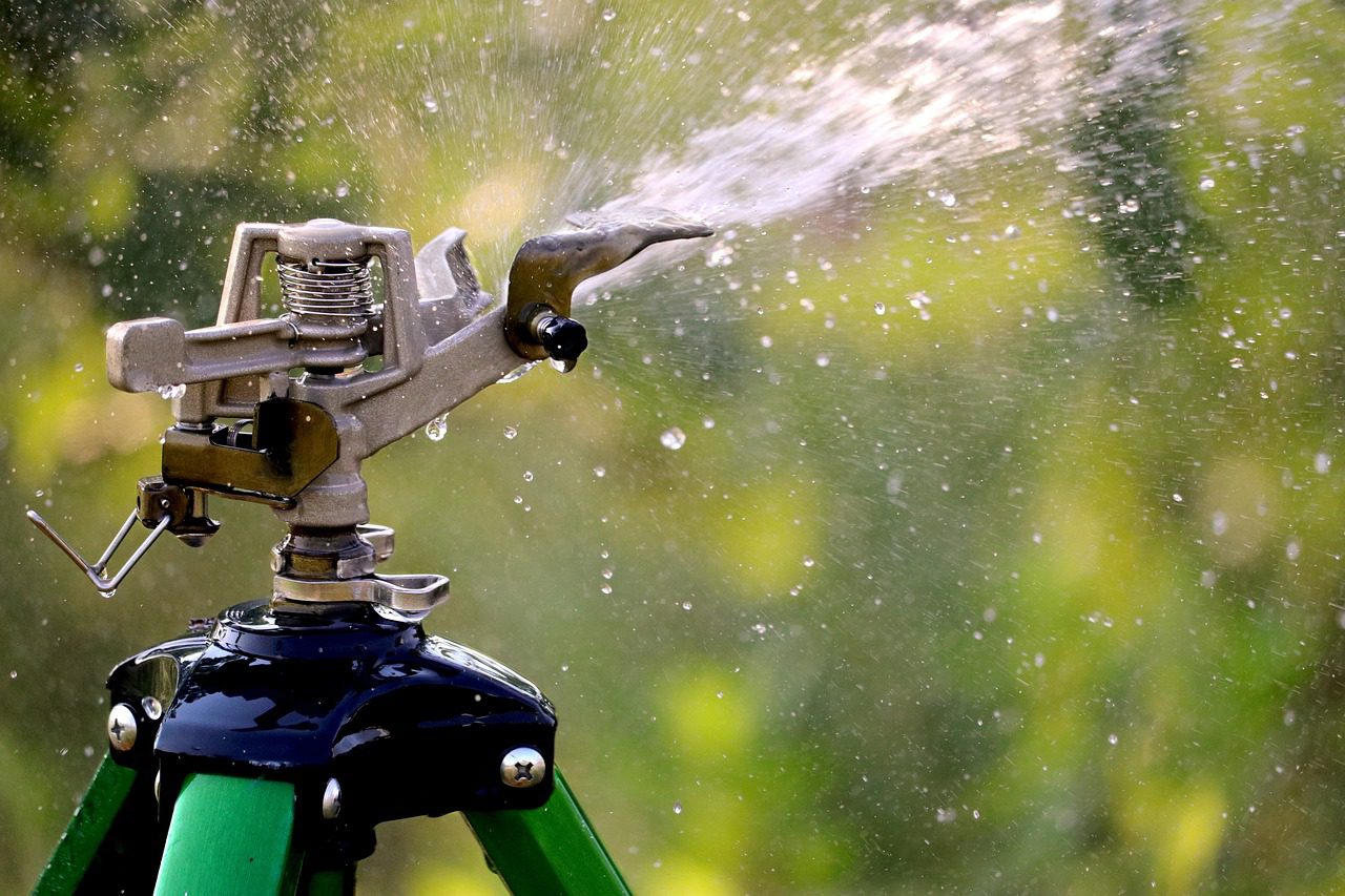 Sprinkler system watering lush green lawn in Atlanta summer heat